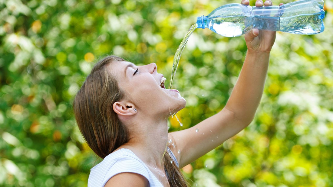 Дівчина п'є воду з пляшки